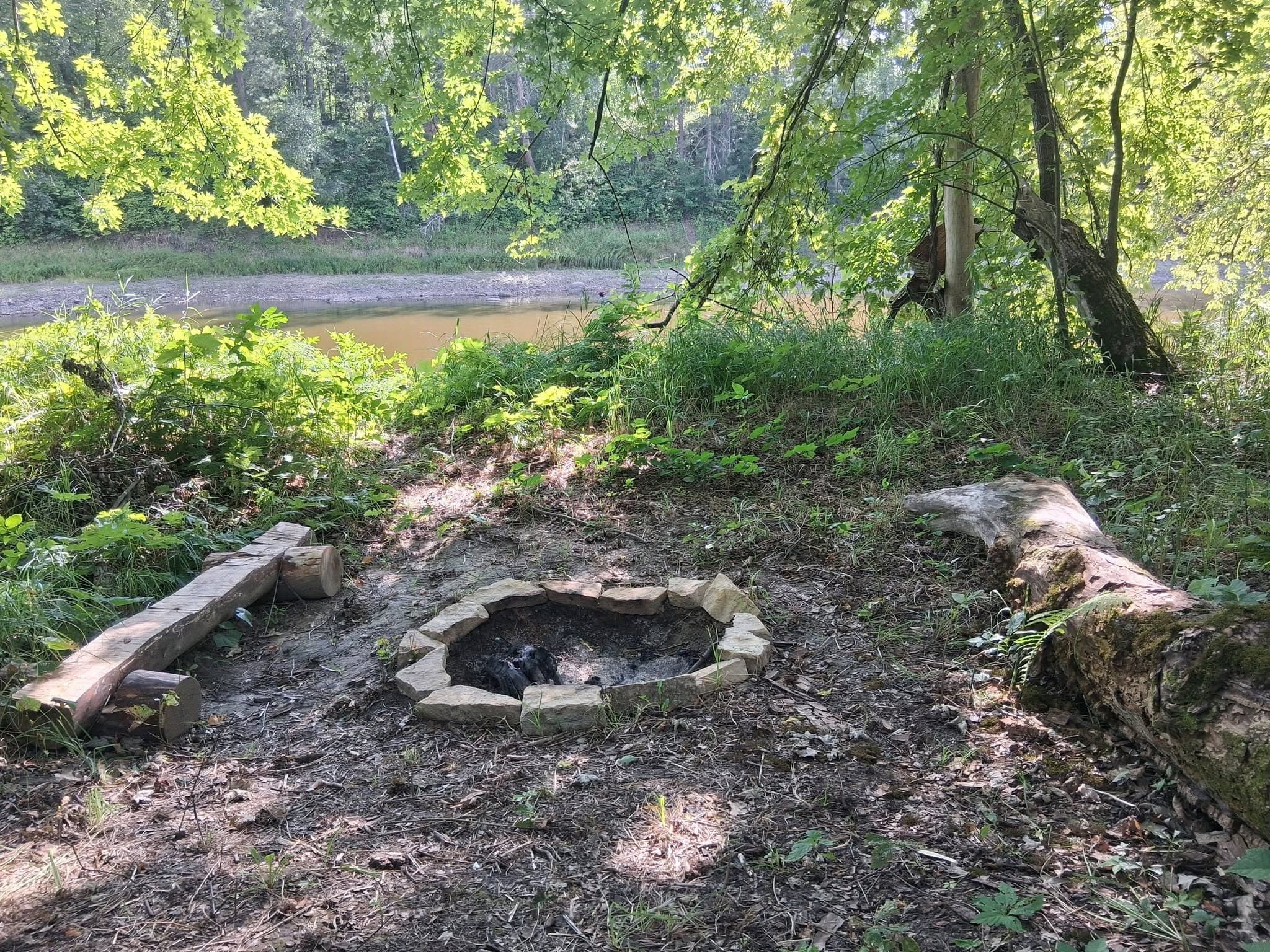 Stone fire pit with log seating near the Mississippi River