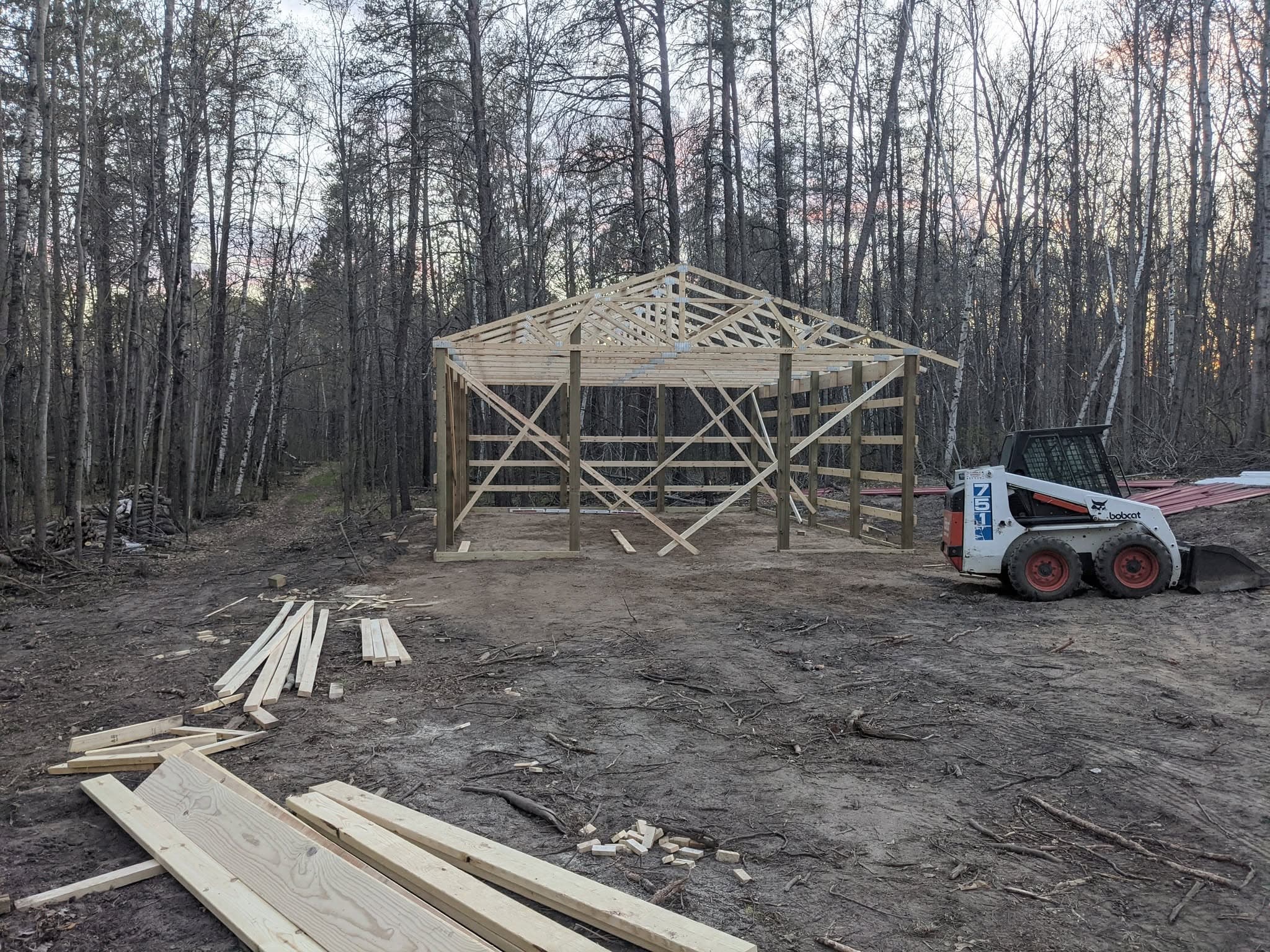 Timber frame pavilion under construction in a forest clearing