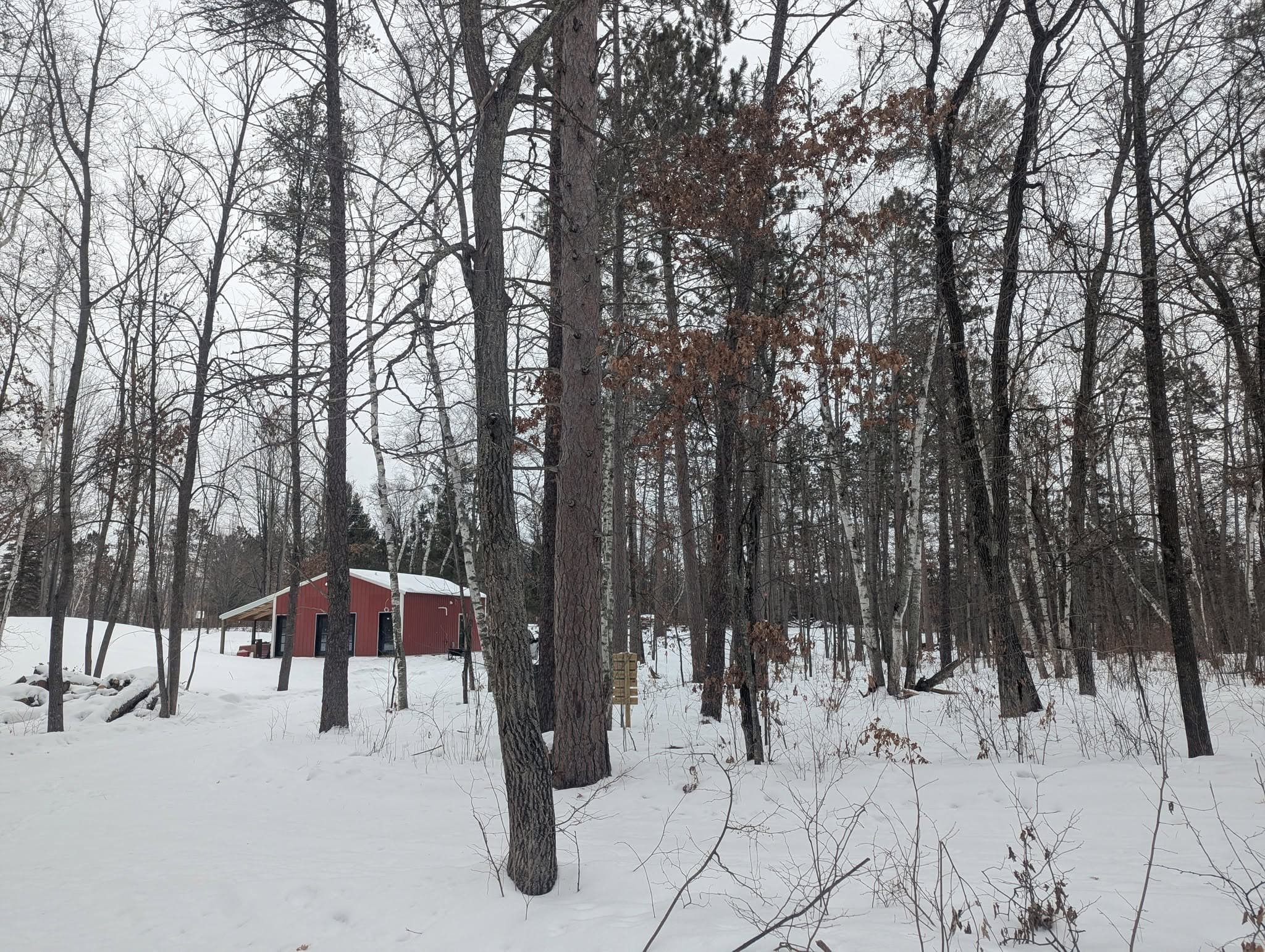Red cabin in a snowy forest clearing at Cuyuna Crossing